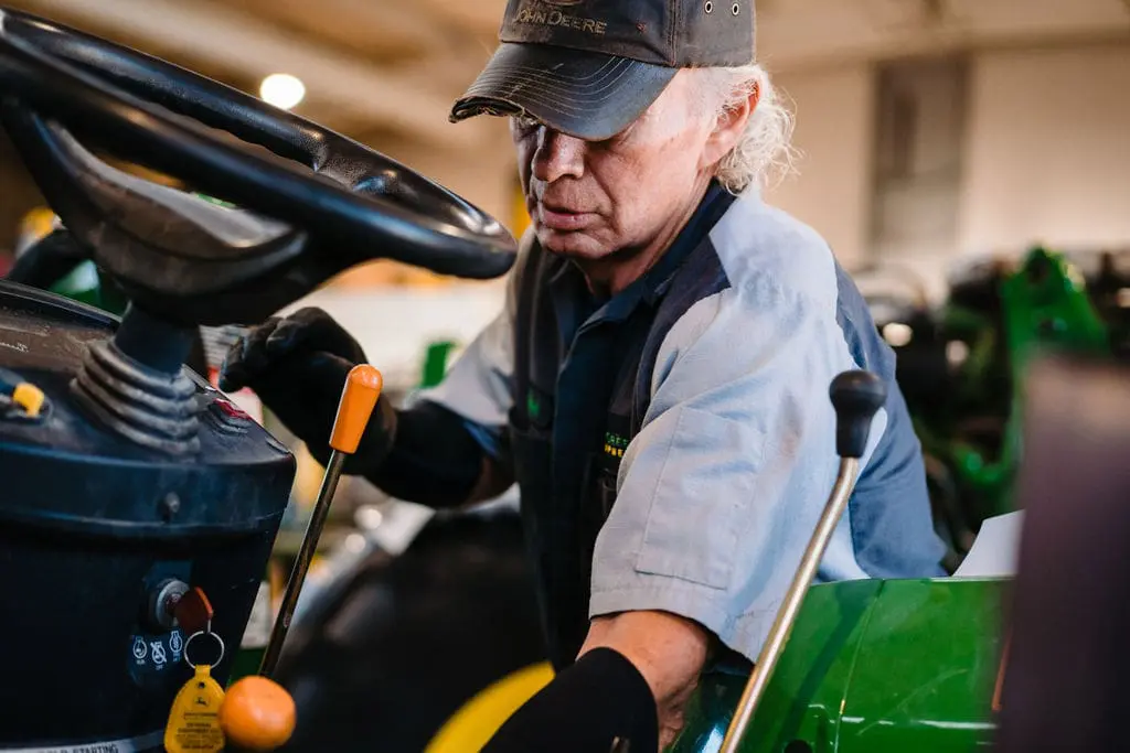 TriGreen John Deere-certified technician works on compact tractor.