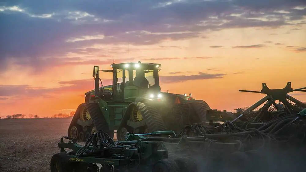 A John Deere 9RX 4WD tractor pulls a tillage implement in a field.