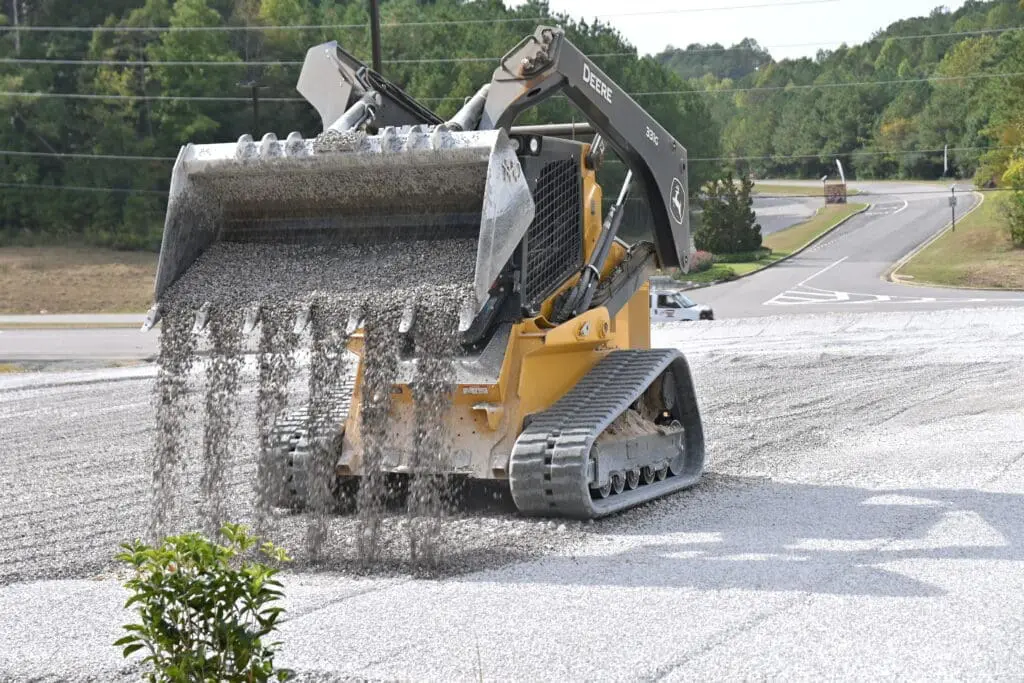 A John Deere tracked skid steer spreads gravel in Leeds, AL