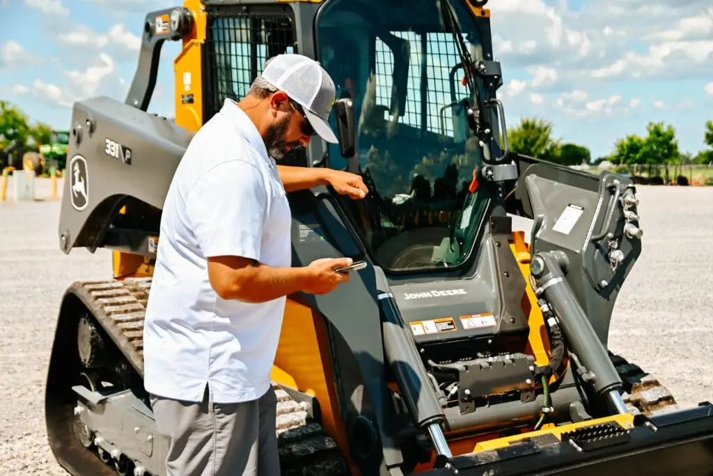 John Deere technician working next to a compact track loader
