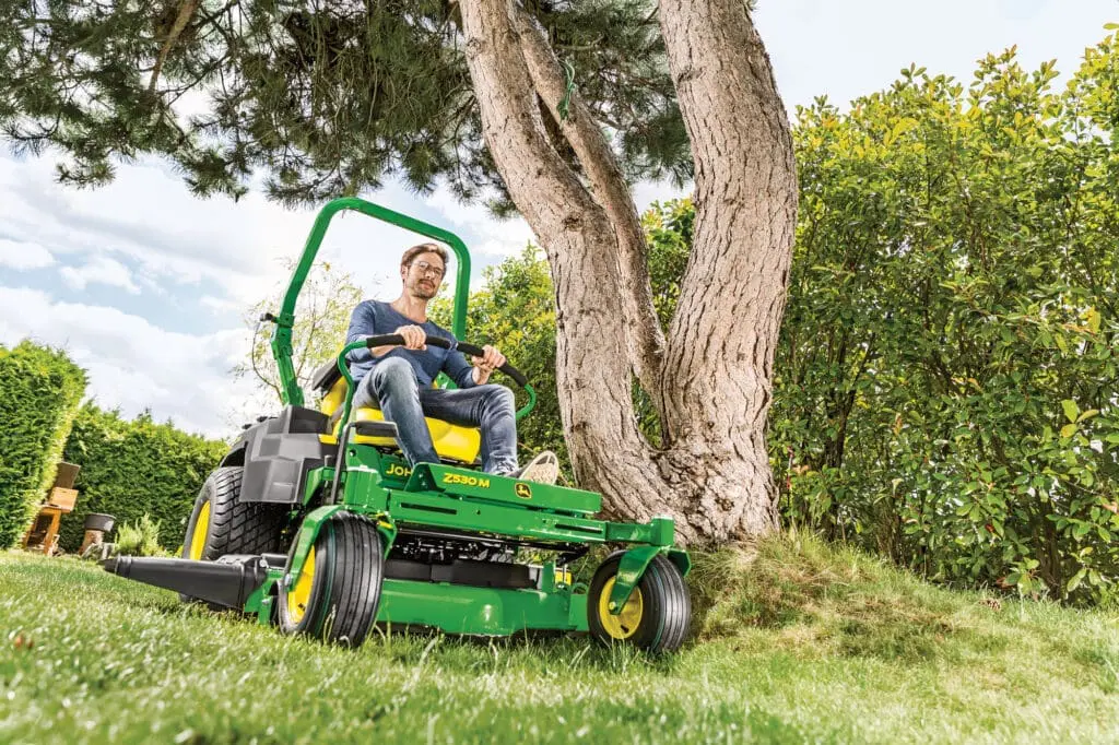 technician using ztrak mower to cut grass around a tree