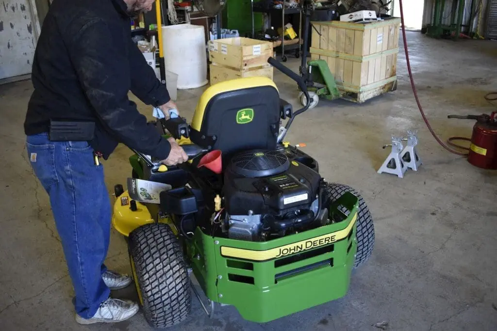 technician puts new oil into mower