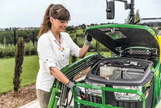 technician servicing a compact tractor