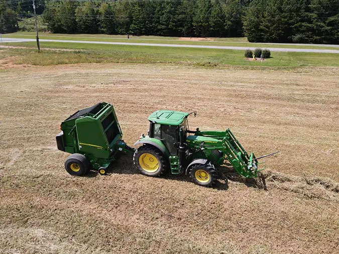 A John Deere 6R tractor bales hay in an Alabama field