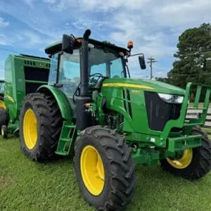 A used John Deere utility tractor with baler for sale on a TriGreen dealership lot