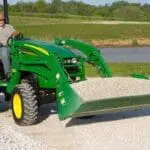 Man drives John Deere compact tractor with 4-in-1 bucket