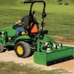 Man smooths gravel driveway with Frontier BB5060L box blade on John Deere 1025R compact tractor