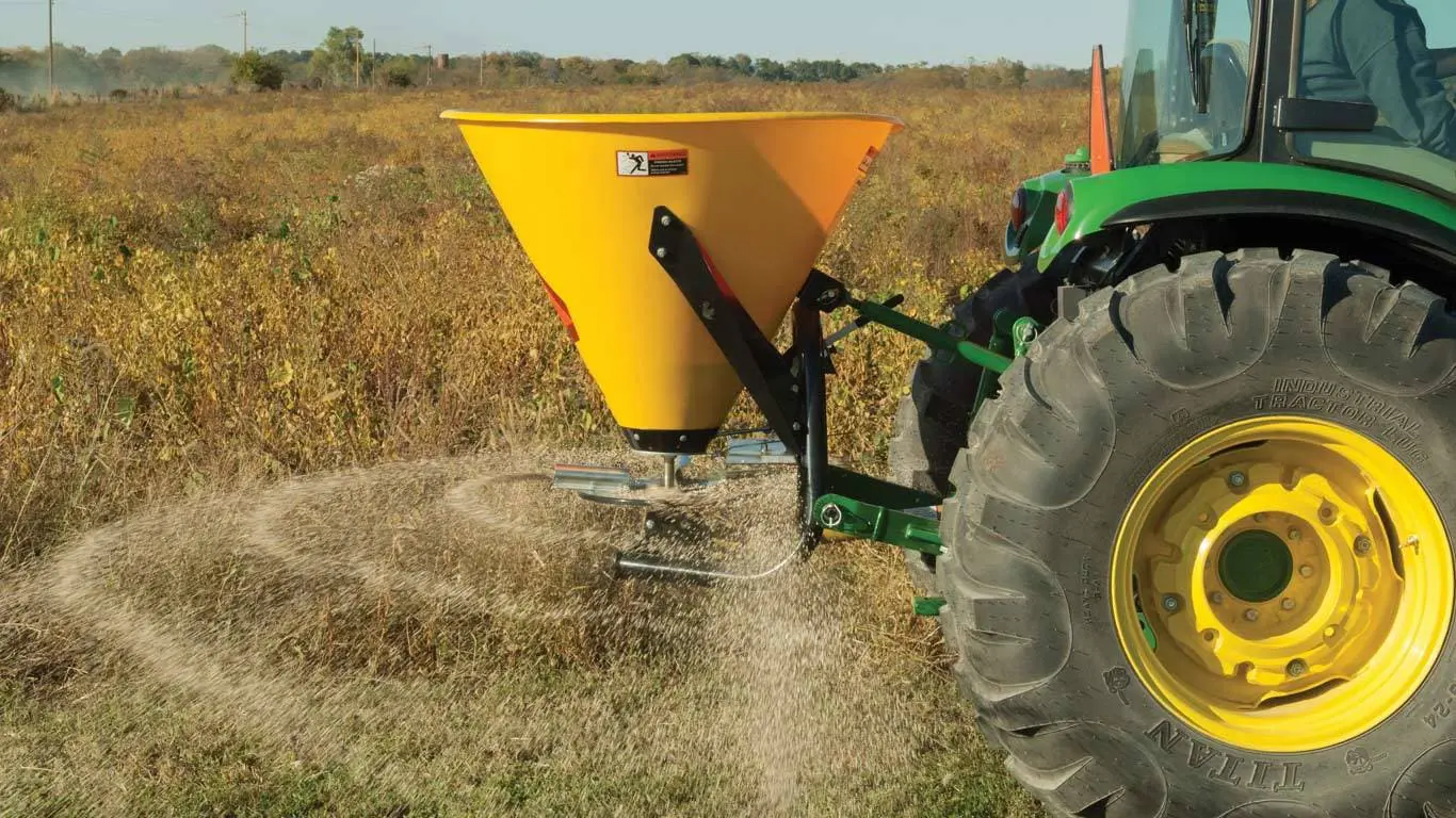 Yellow Frontier SB30B broadcast spreader on back of JohnD eere tractor