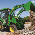 A person dumps a load of gravel with a 3R tractor