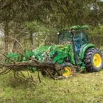 A John Deere 4066R tractor moves brush with a grapple