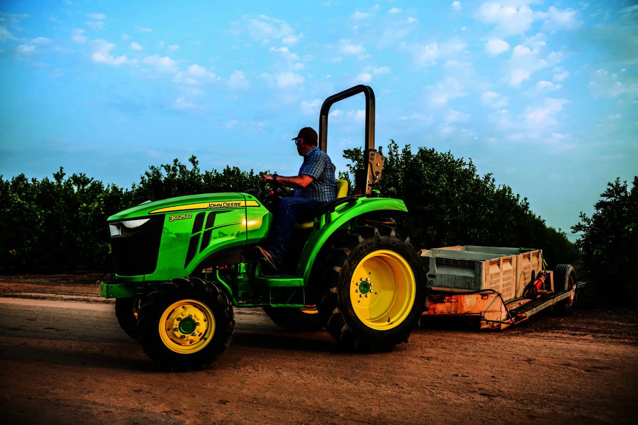 A man works in a nursery with a 3025D John Deere tractor