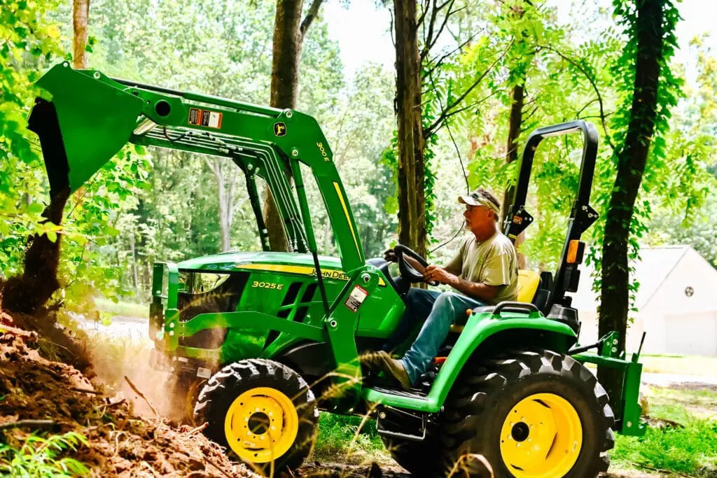 Man moves dirt with a John Deere 3025E Loader