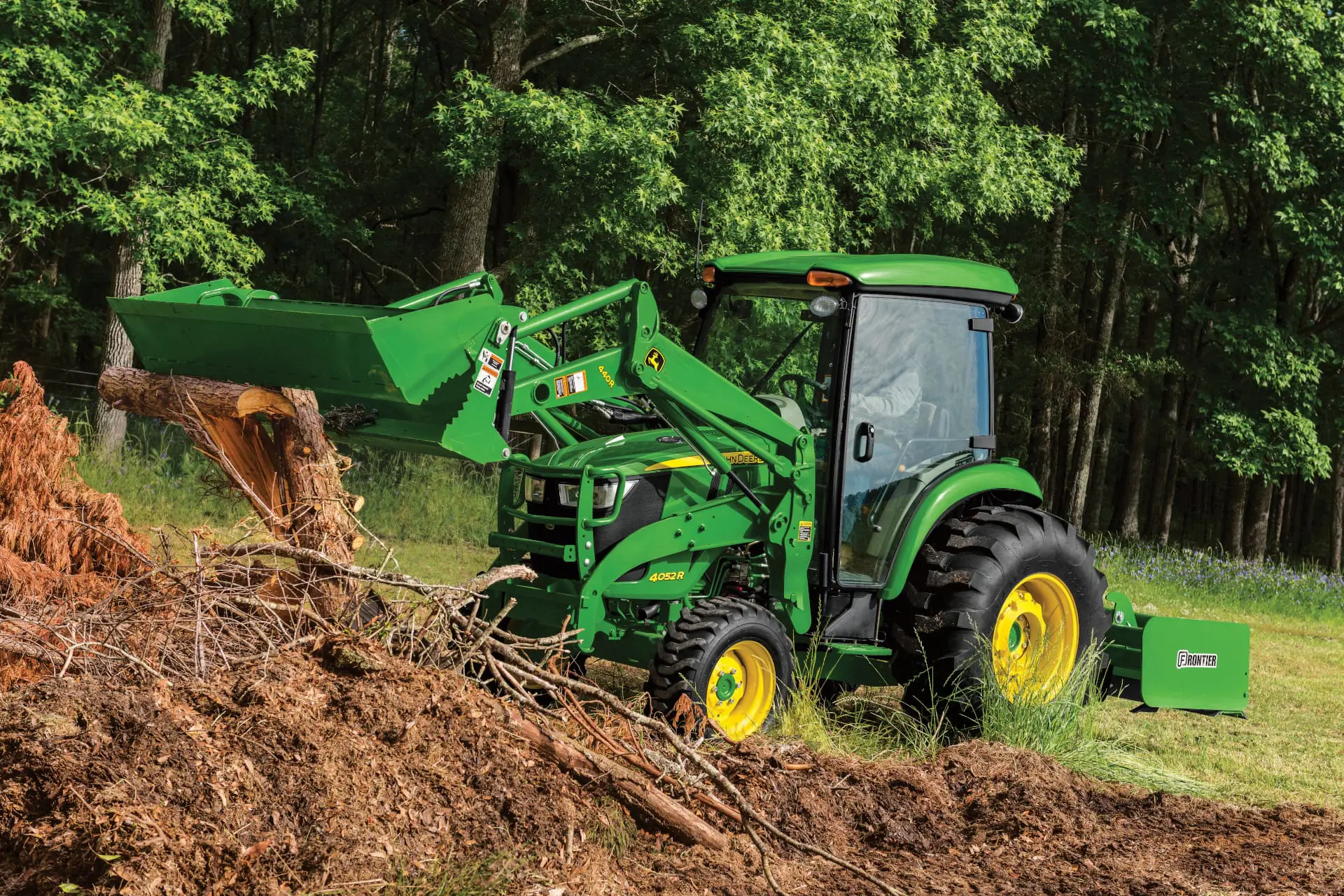 A John Deere 4052R tractor and loader move dirt from a pile