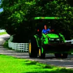 A John Deere tractor loader carrying dirt on a driveway