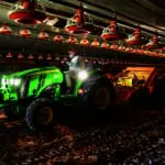 A poultry farmer works in a barn with a 4066M tractor