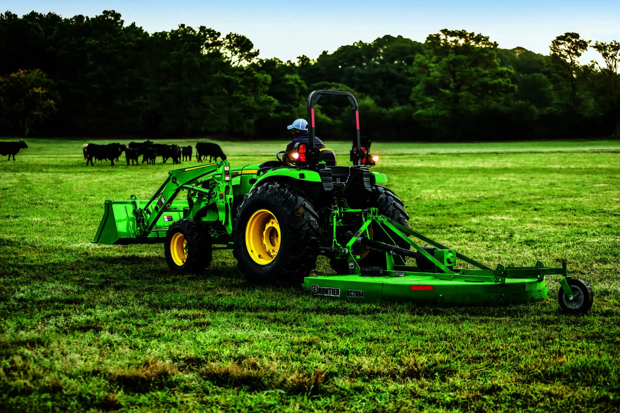 A person bush hogs a pasture with a John Deere 5066M
