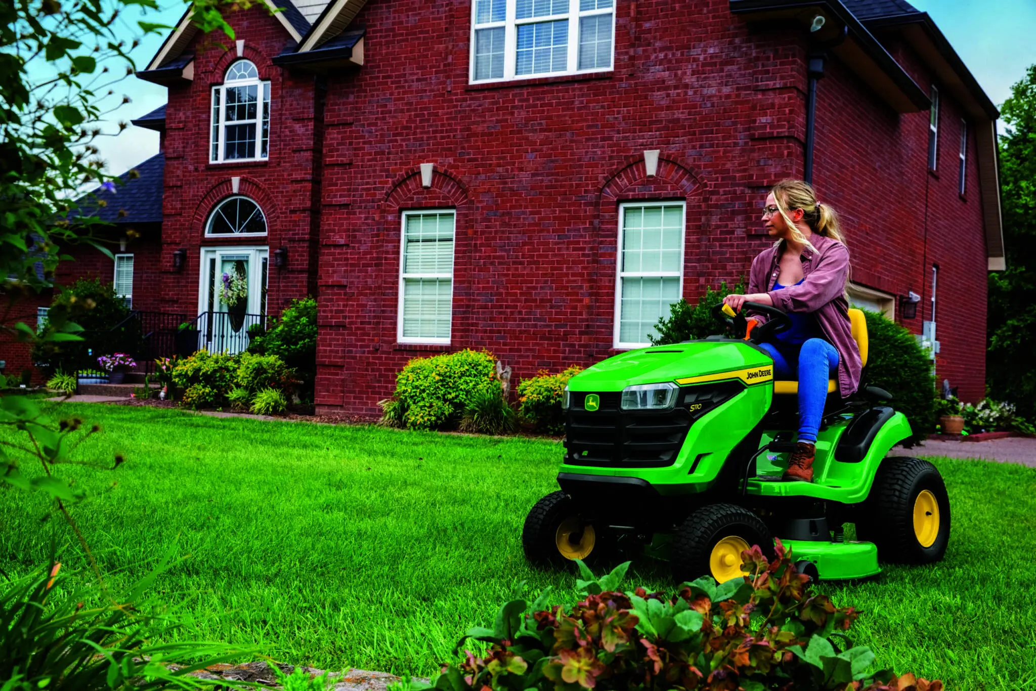 A woman mows with an S110 lawn mower