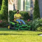 A man mows around flower beds with a Deere Z330R zero turn mower