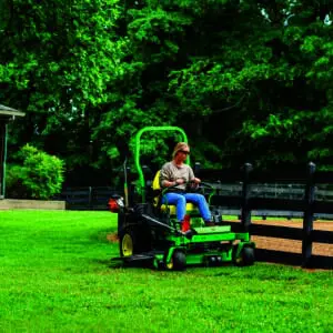 A person mows along a fence with a Deere Z730M zero turn