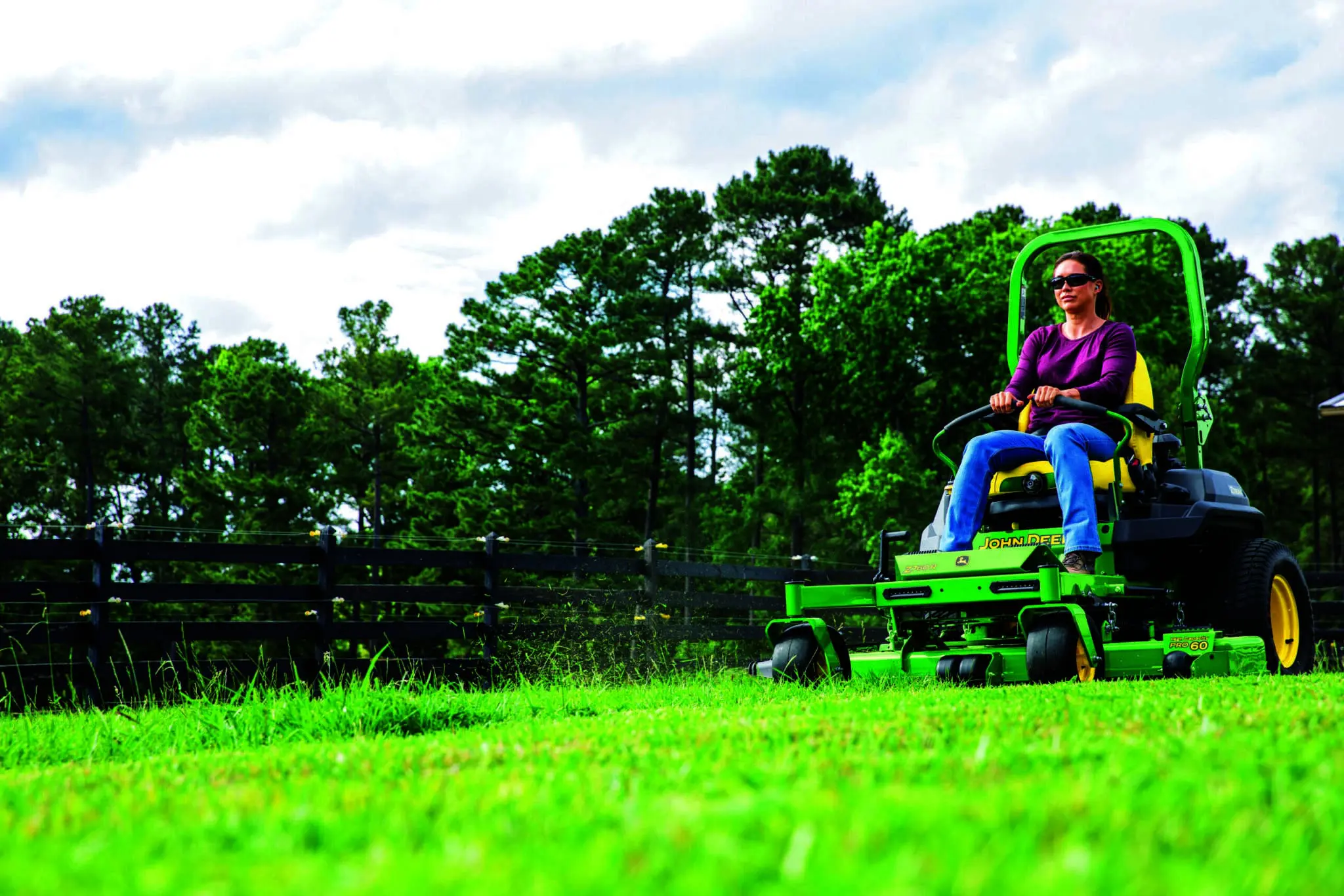 A woman mows a yard with a John Deere Z760R