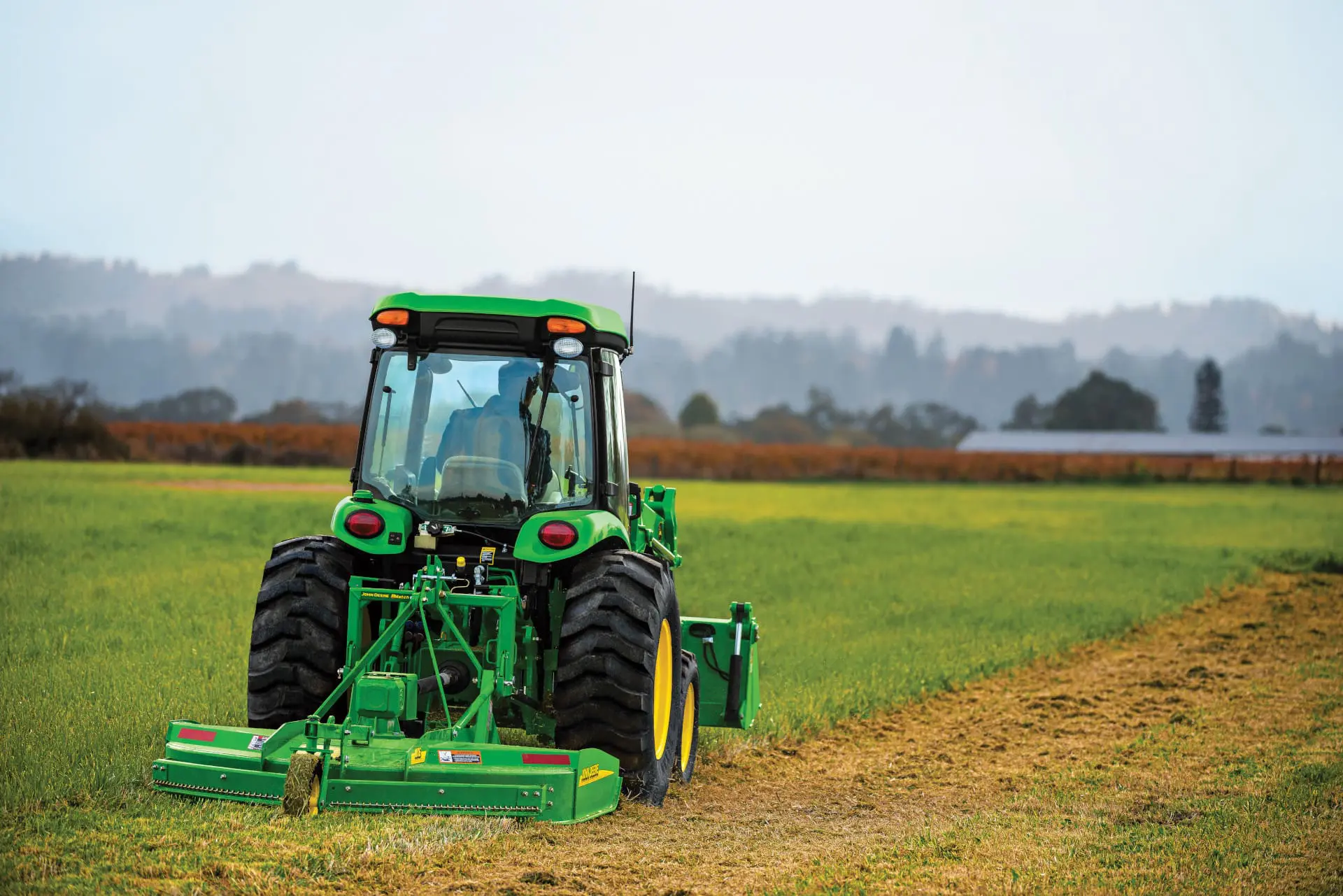 A John Deere 4052R mows a pasture