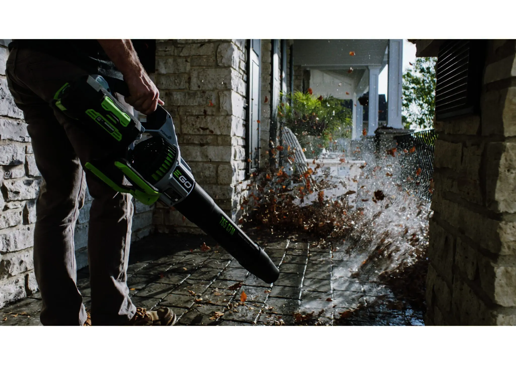 A person uses an EGO leaf blower on a patio