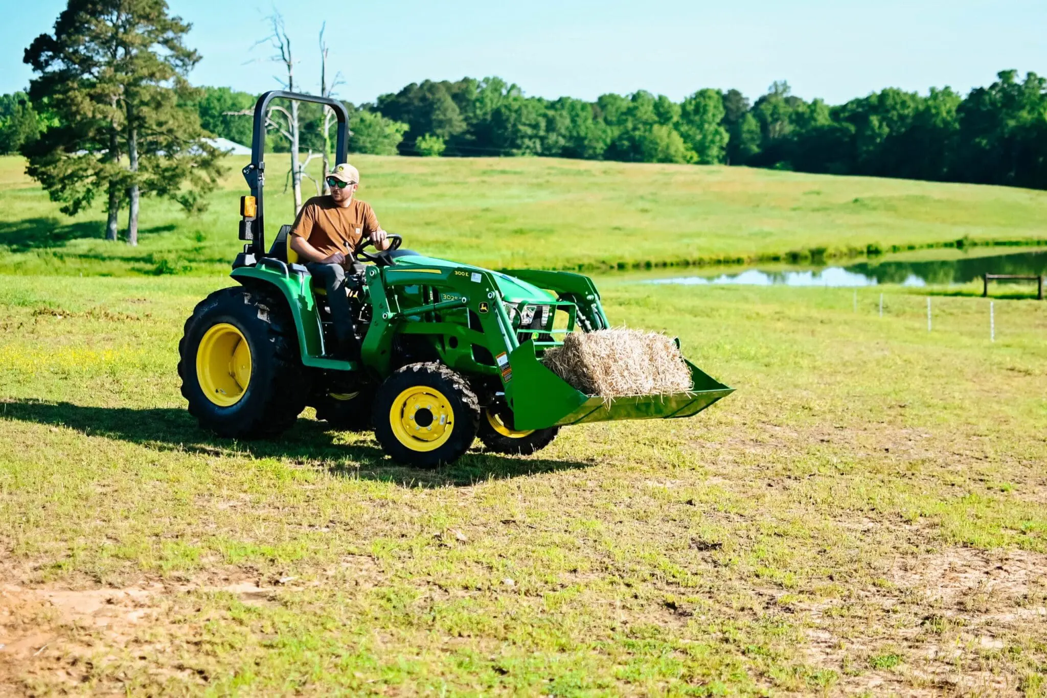 Man mows brush with John Deere 3025E Compact Tractor
