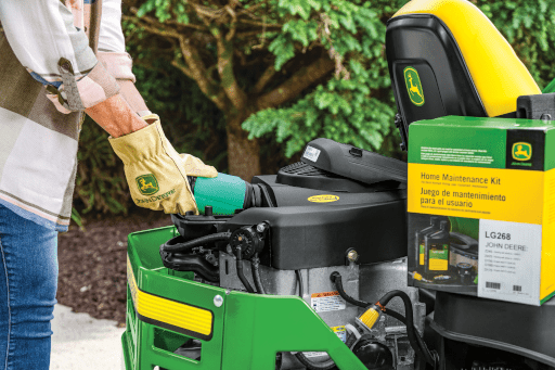 A person completes a DIY oil change on a lawn mower with JD parts