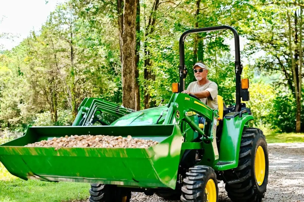 Man carries load of gravel with John Deere 3025E Compact Utility Tractor