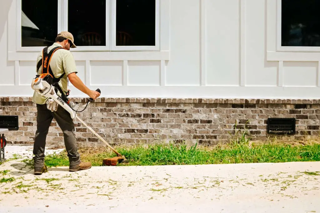 Man trims weeds in flowerbed with STIHL FS311 string trimmer