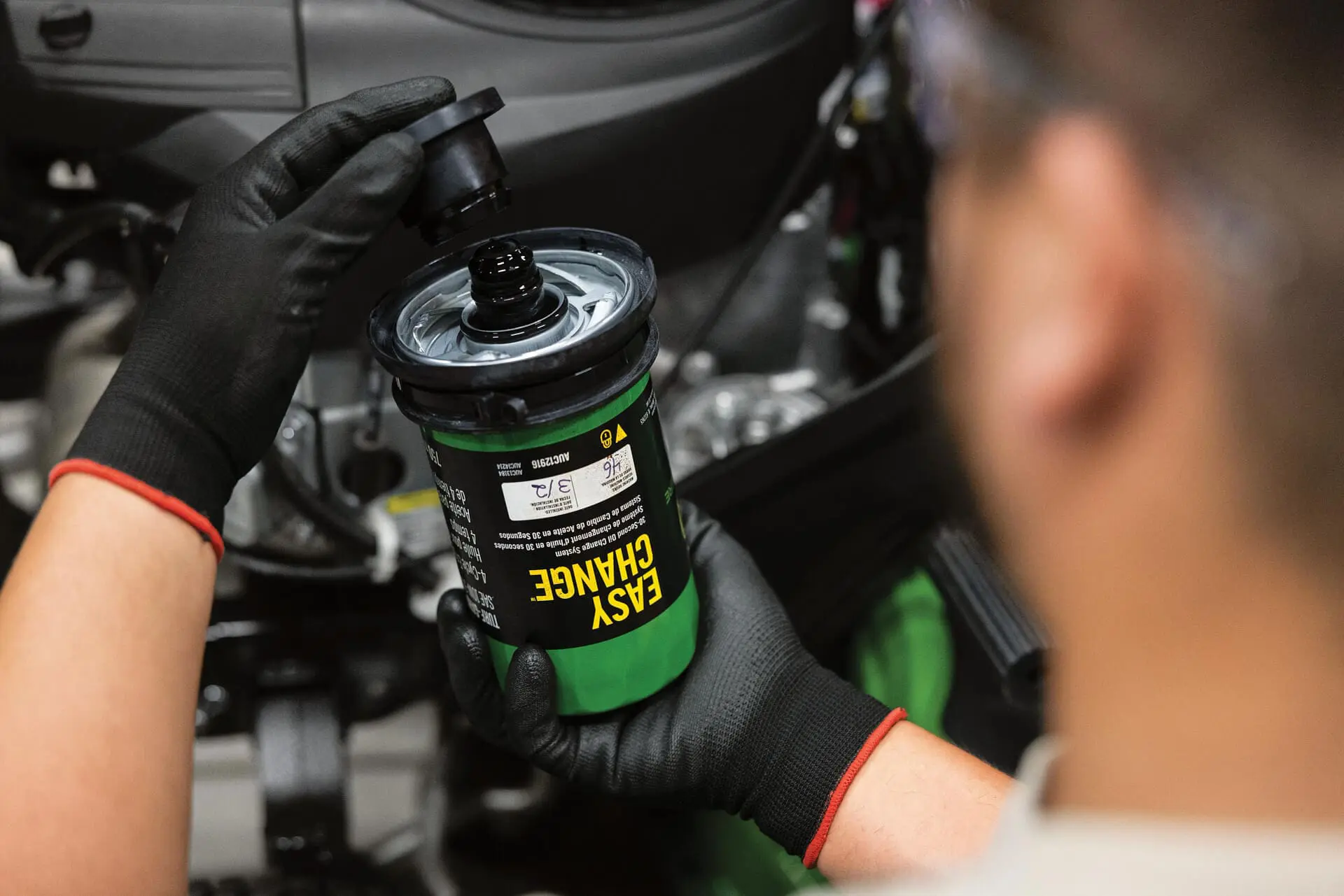 Technician changes Easy Change oil filter on John Deere lawn mower
