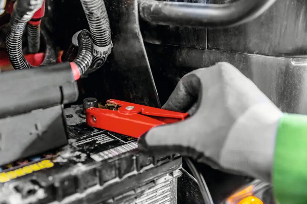 gloved hand places battery lead on terminal