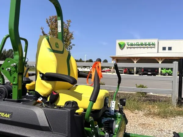 John Deere commercial zero turn mower parked in front of TriGreen Equipment dealership in Athens, Alabama with orange ribbon tied on handle.