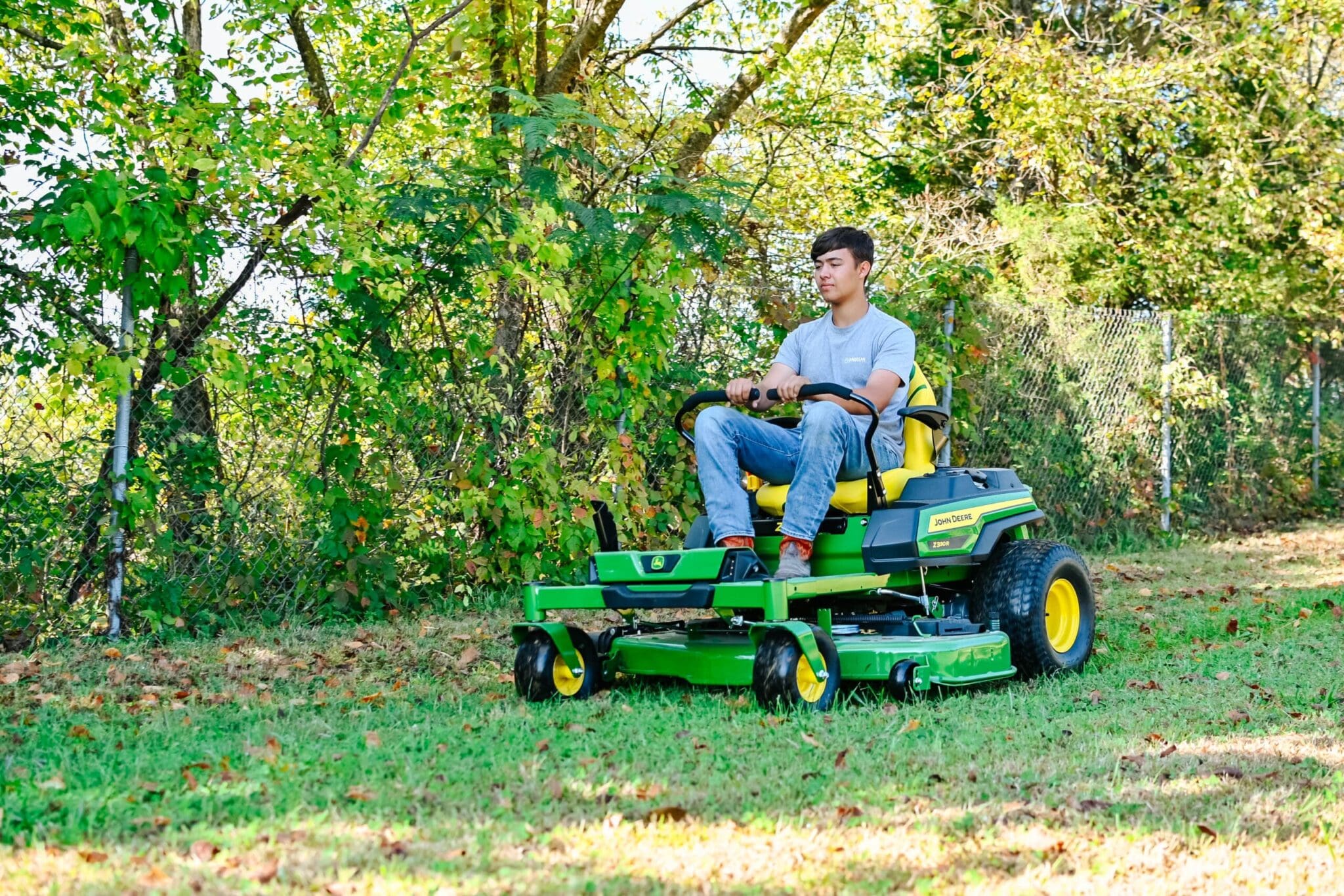 A person mows a yard on a John Deere Z300 zero turn mower