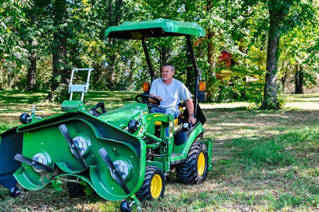 A property owner driving a mini tractor with mowing deck