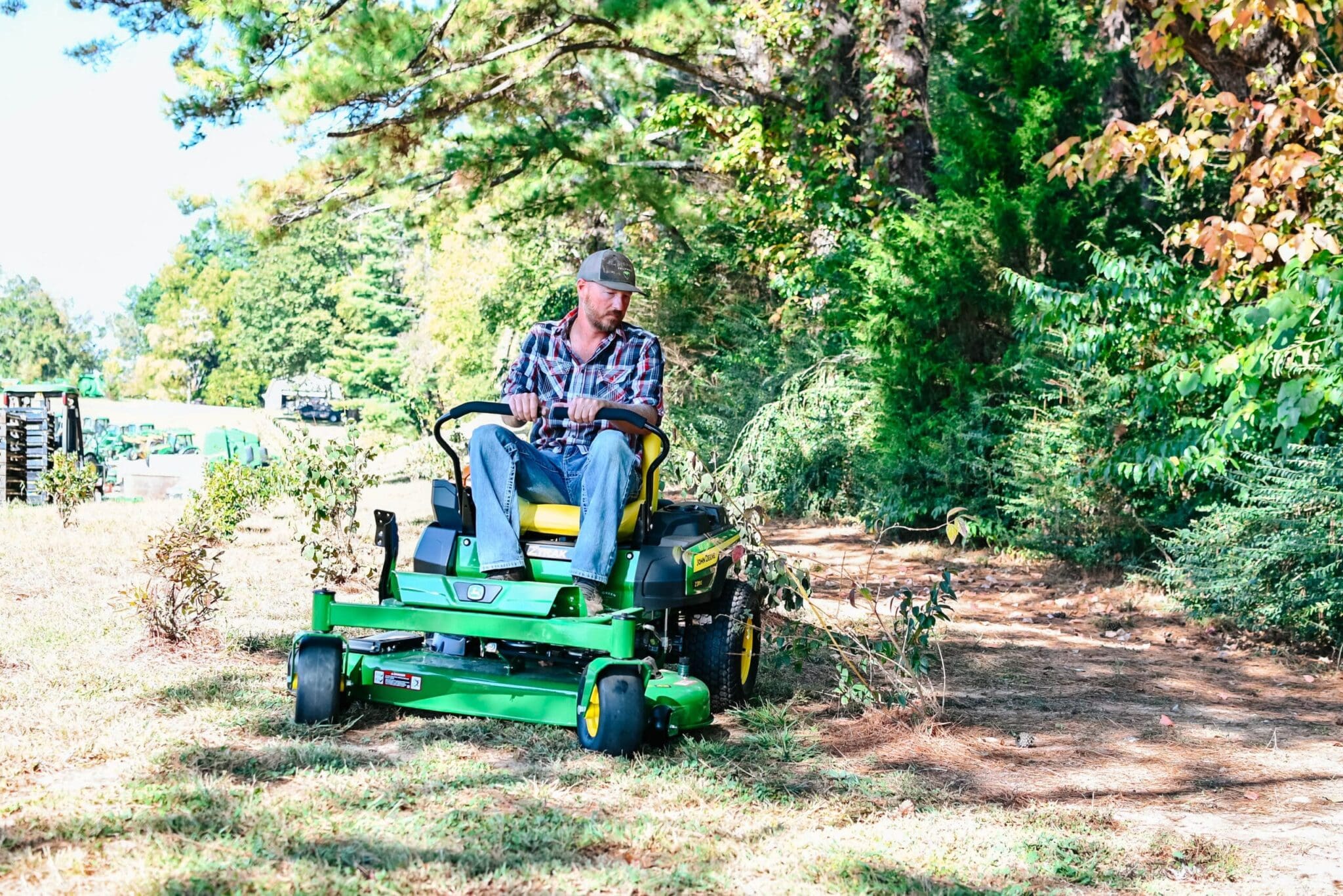 A man mows around landscaping on a John Deere zero turn mower