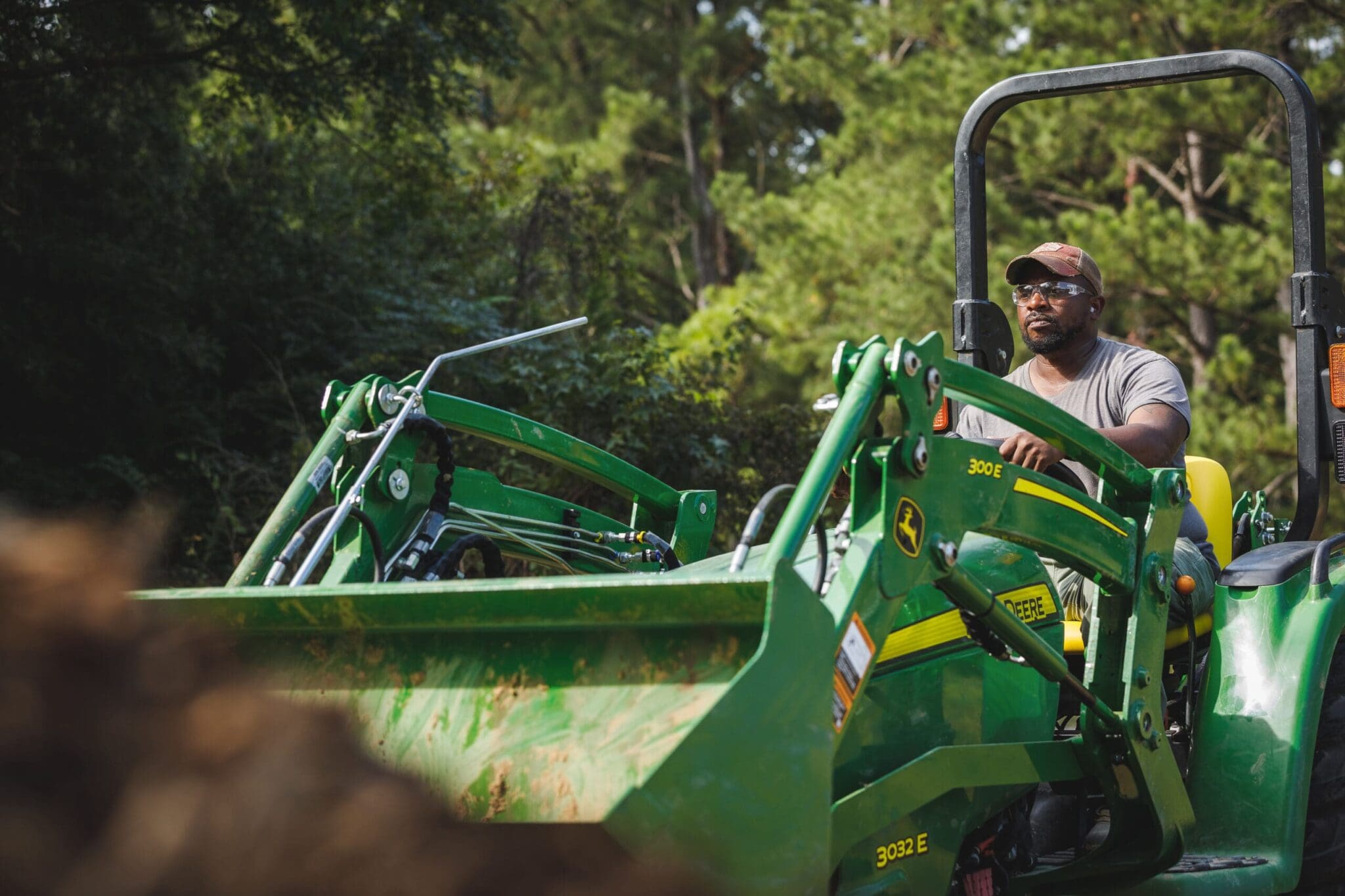 Technician moving dirt with compact utility tractor