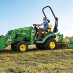 A person tills the ground with a John Deere 1025R tractor