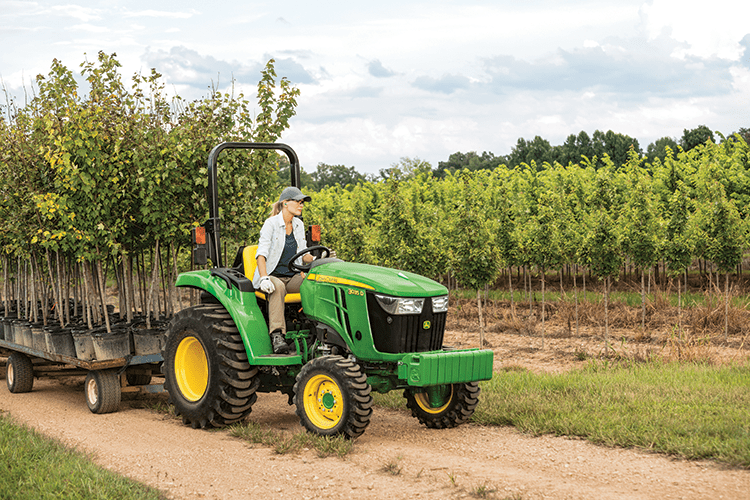 A John Deere tractor pulls a load of trees at a nursery