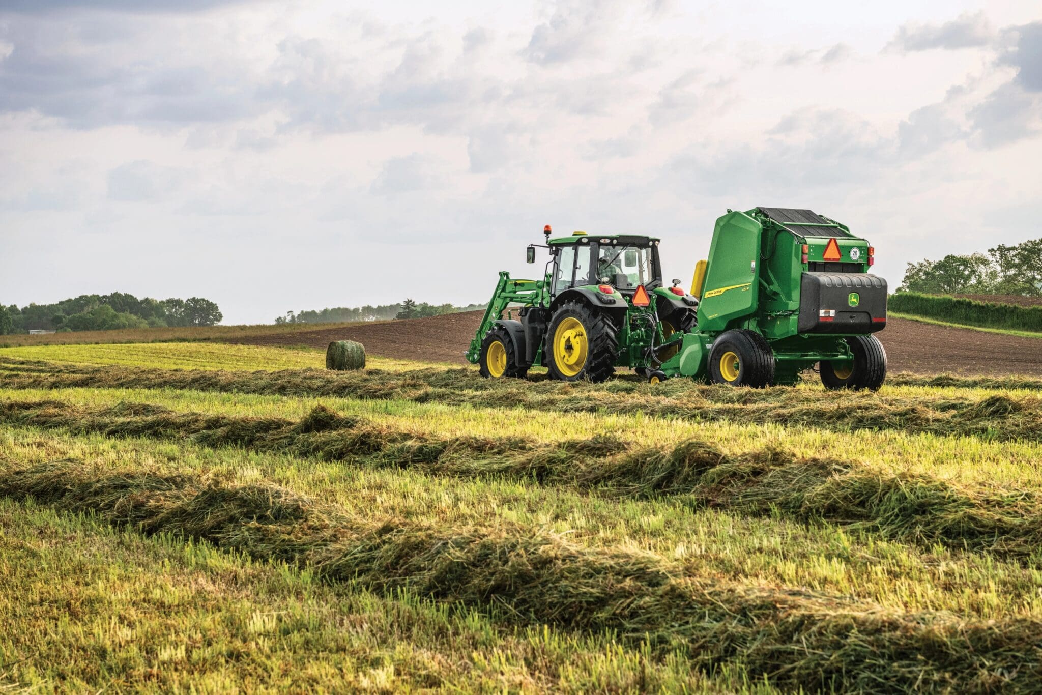 large tractor with round baler attachment