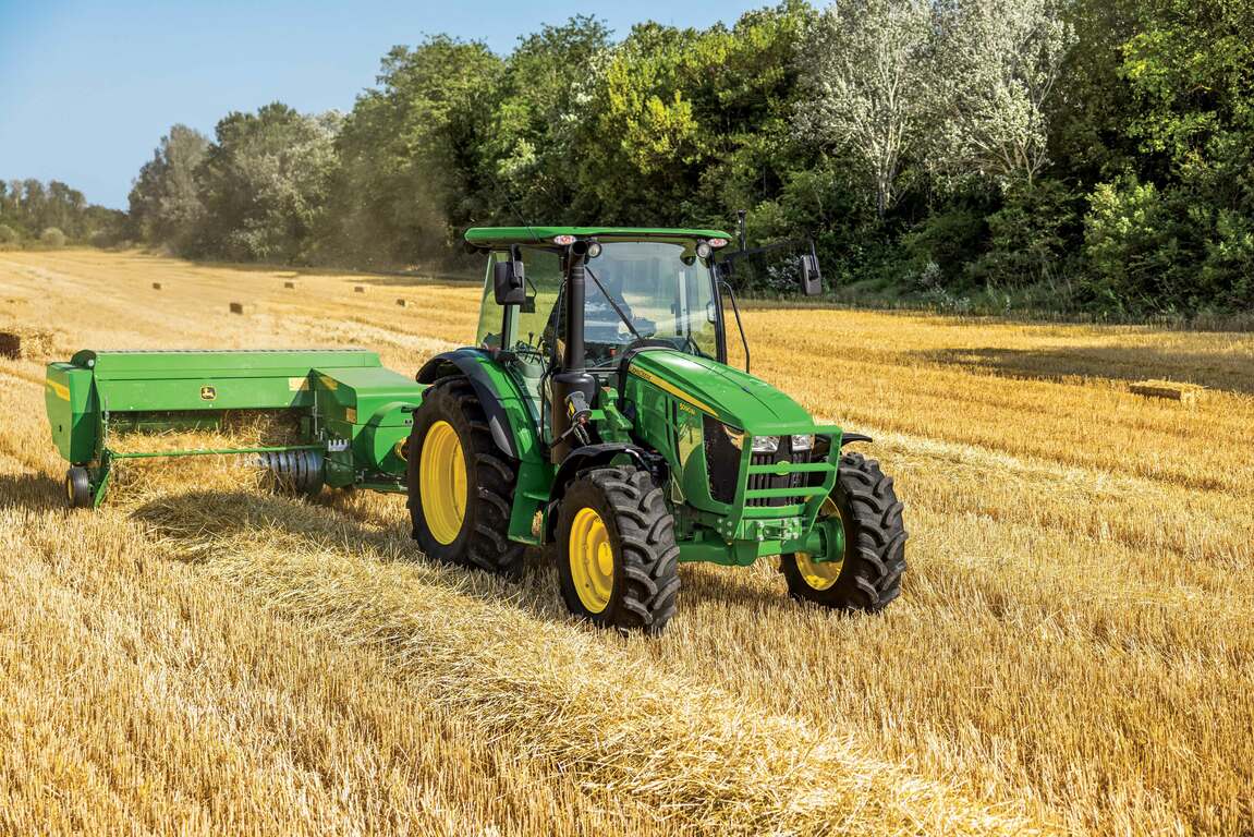 tractor with baler attachment being used to may hay bales