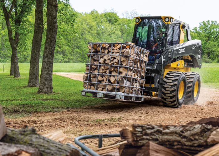 A John Deere p-tier skid steer moves a pallet of wood