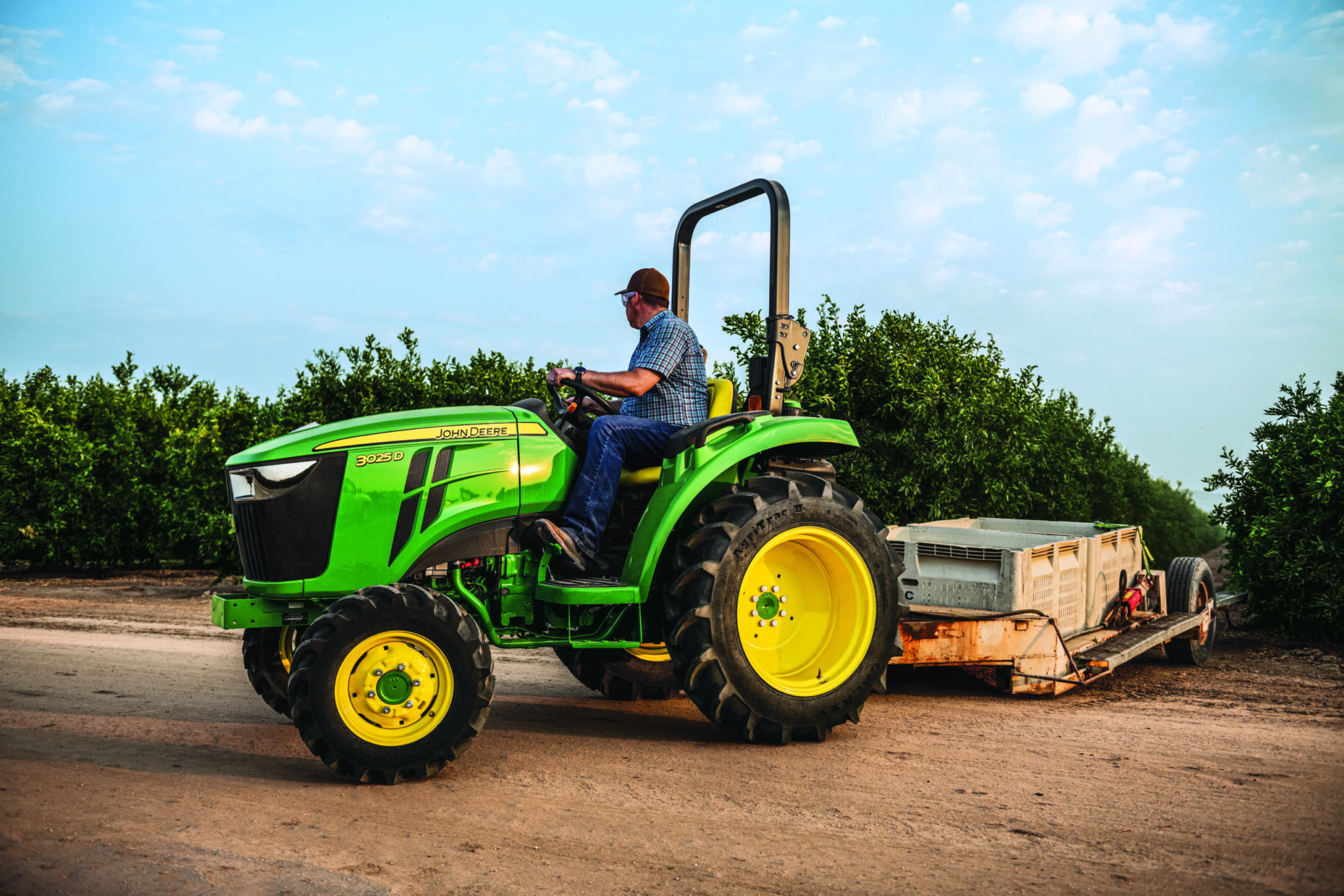 A man works in a nursery with a 3025D John Deere tractor