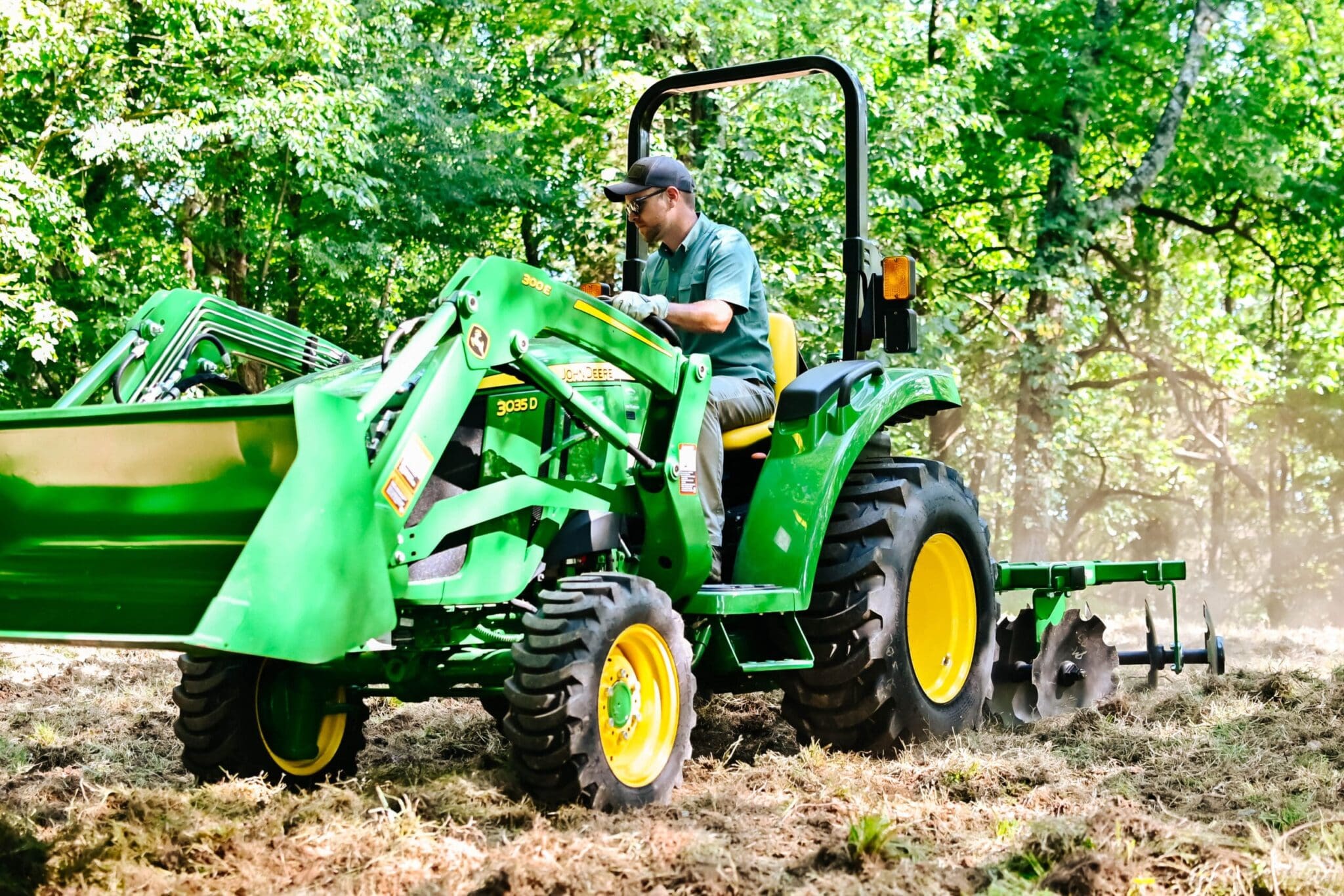 A man disks a food plot with a Deere 3035D tractor