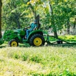 A man bush hogs with a John Deere 3043D tractor