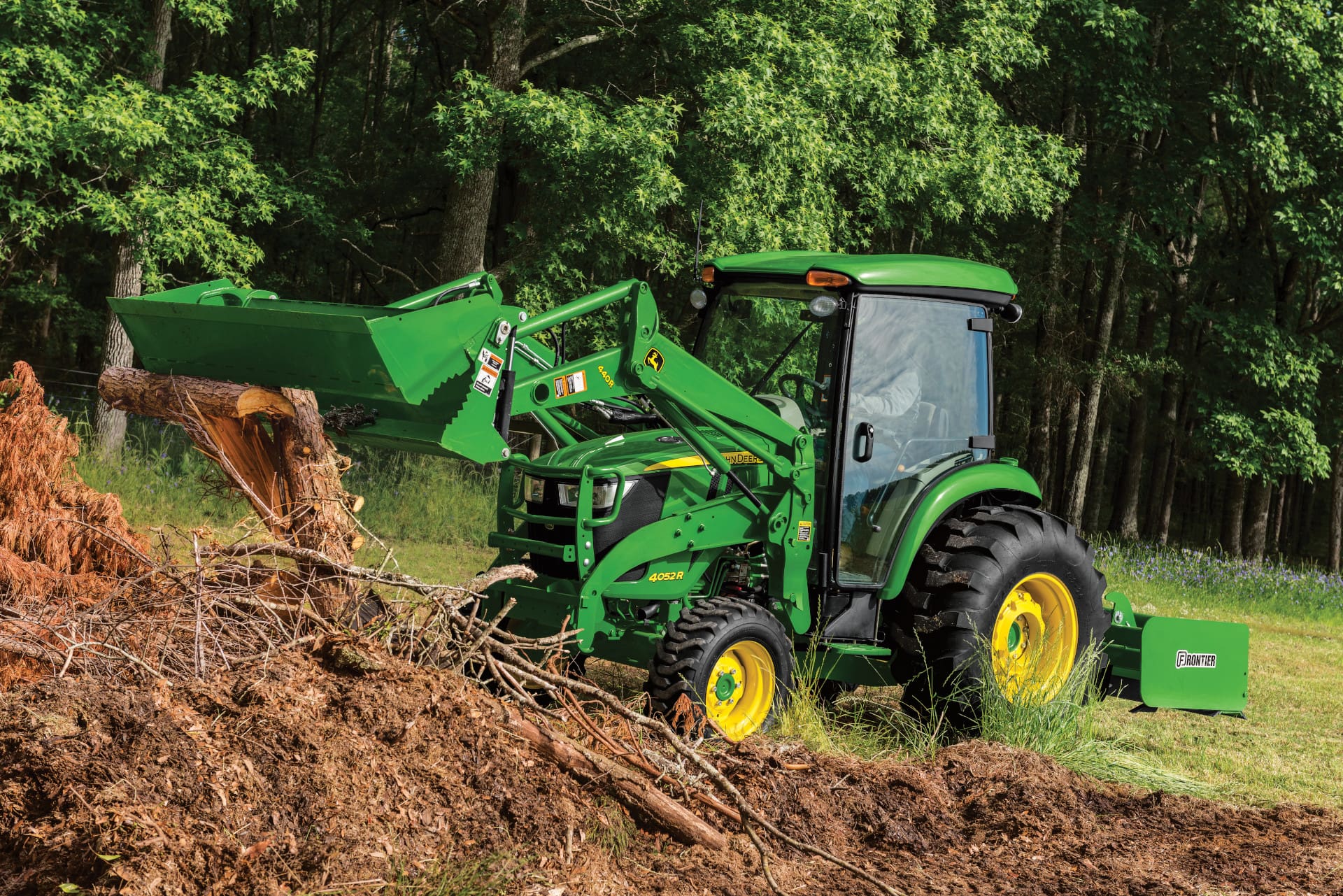 A John Deere 4052R tractor and loader move dirt from a pile