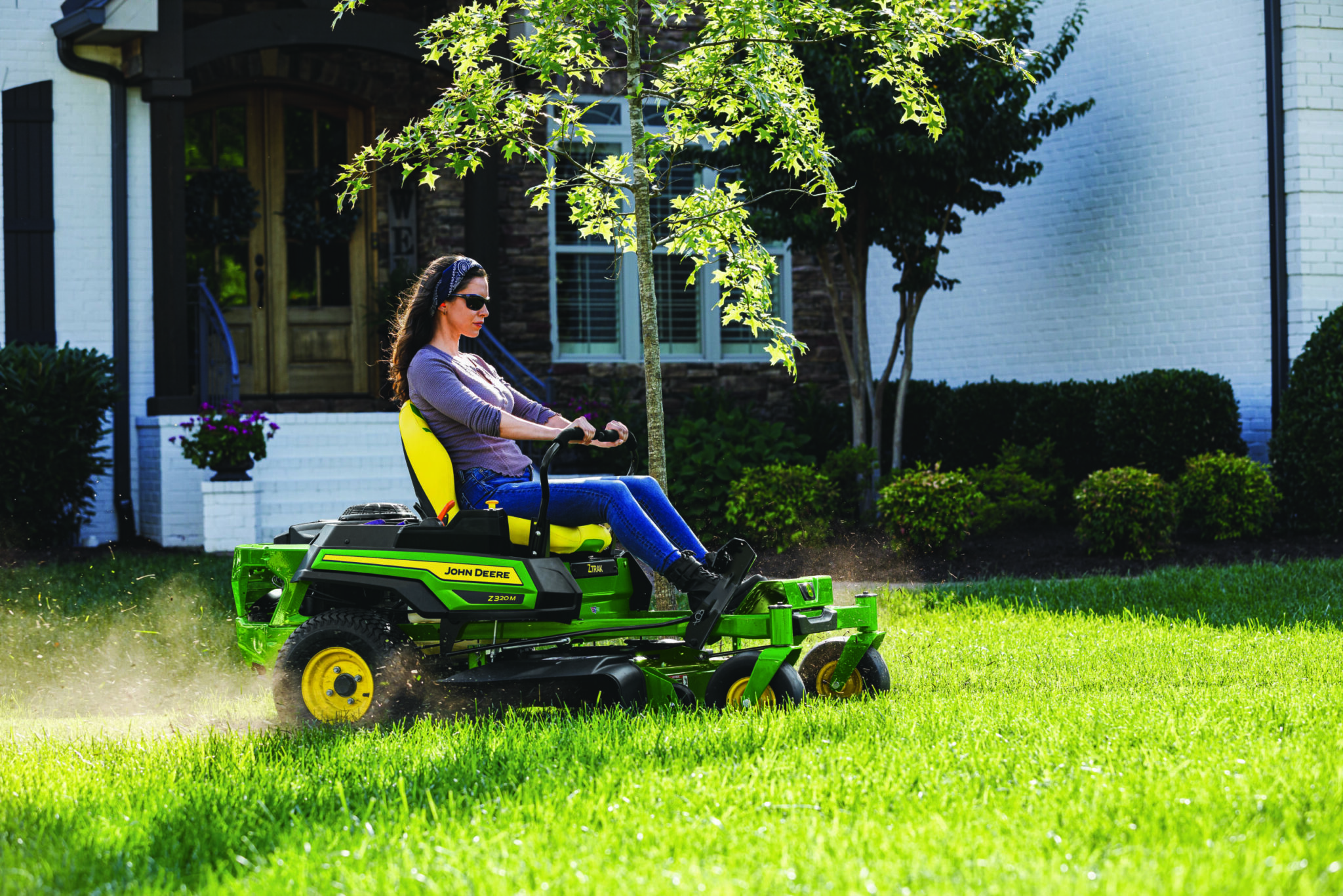 A woman mows with a Deere Z320R mower