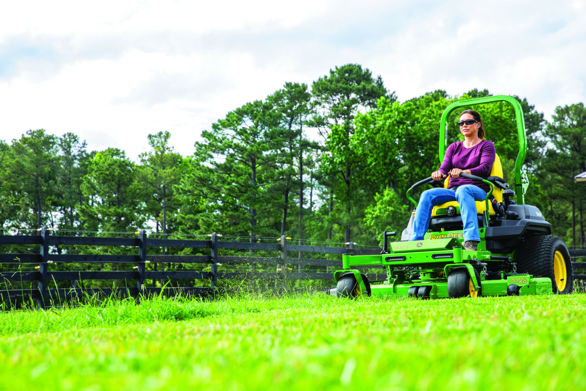 A woman mows a yard with a John Deere Z760R