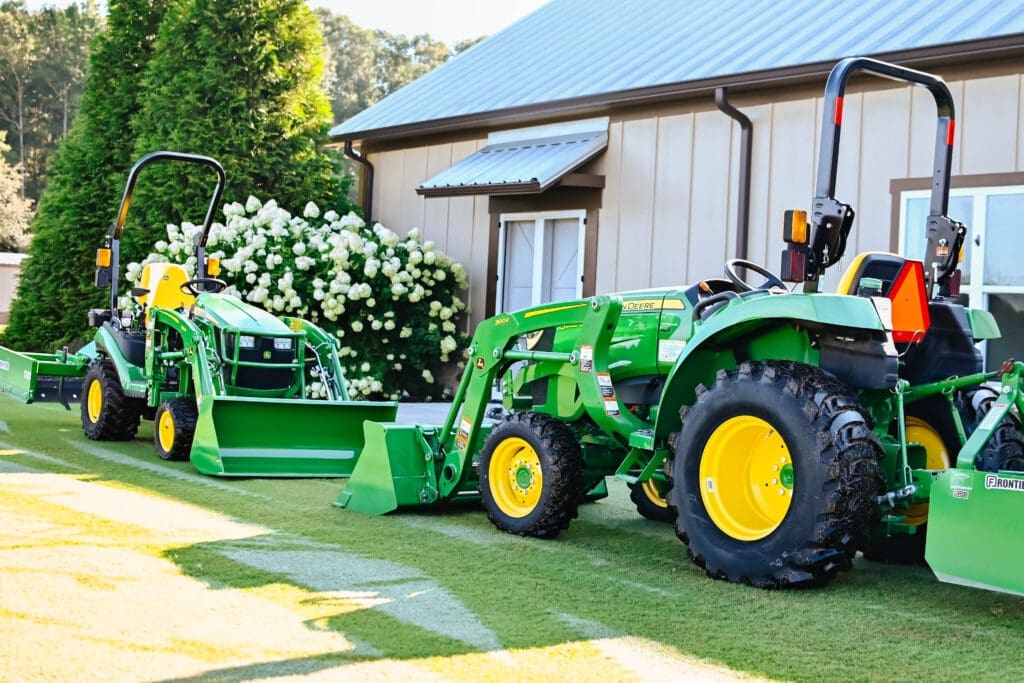 Two John Deere mini tractor packages in front of a house