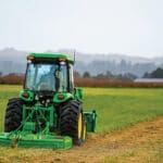 A John Deere 4052R mows a pasture